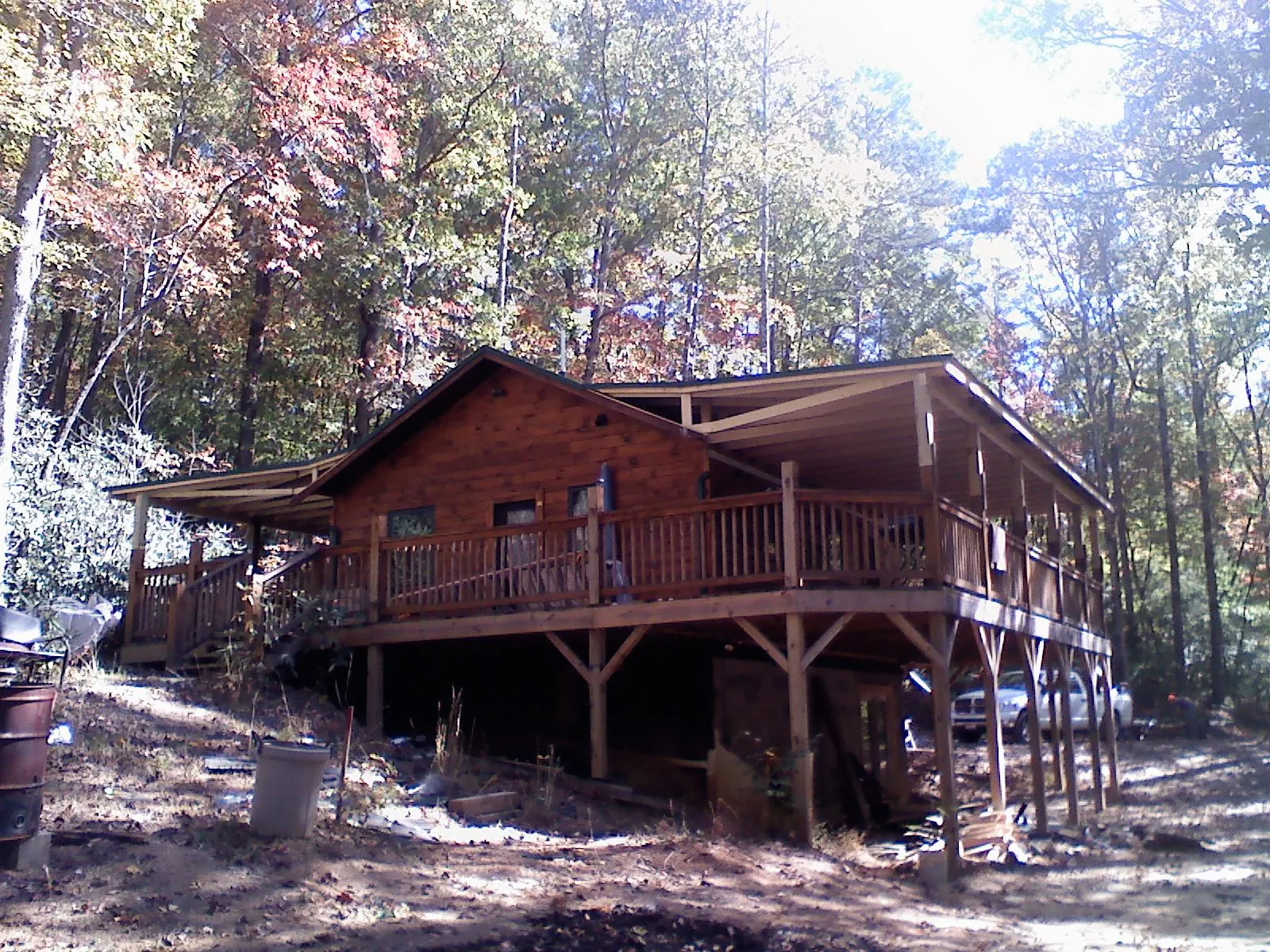 Log cabin with a wraparound porch and metal roof in the fall in Independence
